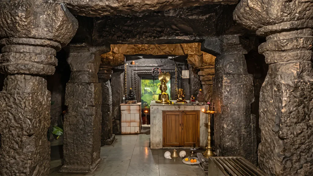 Rustic stone and timber architecture of Raireshwar Temple surrounded by mist on the high plateau.